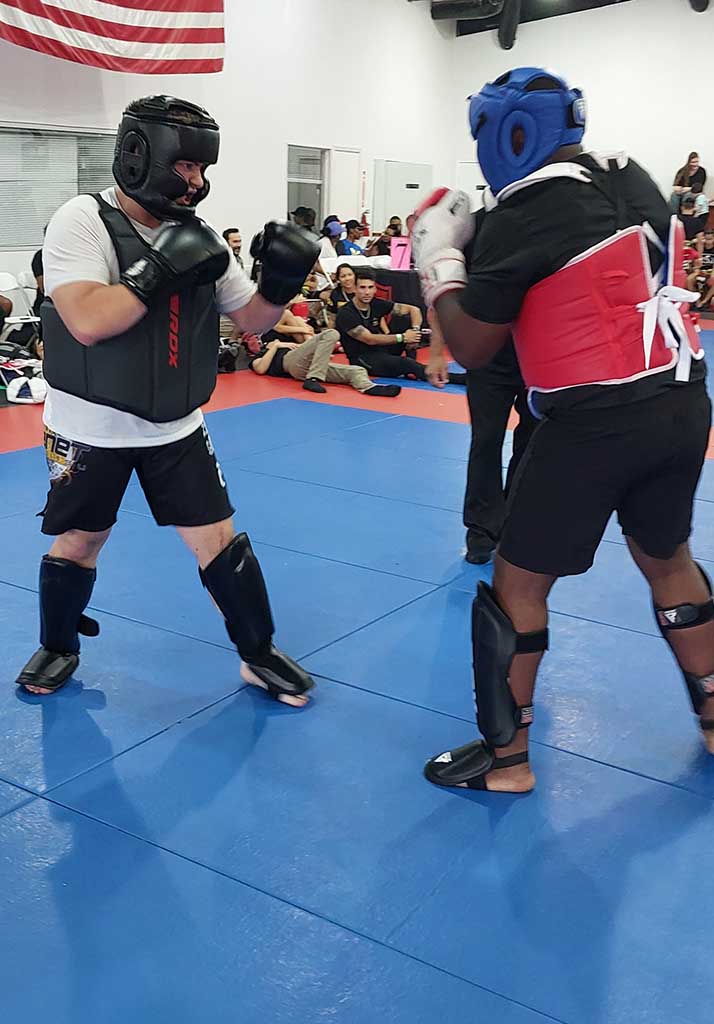 Student training Muay Thai at 10th Planet Beaumont, performing a roundhouse kick on pads