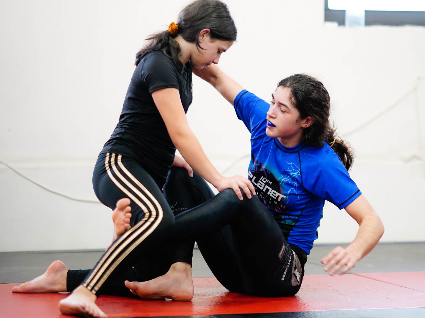 Two young students drilling no-gi jiu-jitsu, one seated in guard and one kneeling, during a kids class at Radius Martial Arts in Fairfield, CT